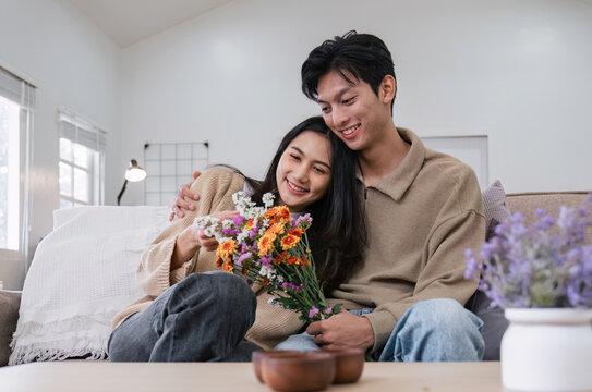 Young couple hugging and showing their love to each other. And give bouquets of flowers to each other on special days or Valentine's Day. On the sofa in the living room