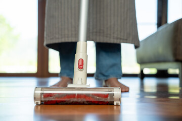 Housewife using vacuum cleaner on the floor. Wearing an apron to clean the living room at house....