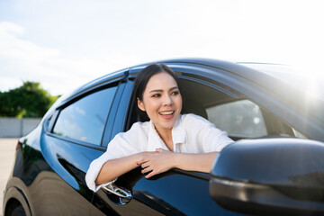 Young beautiful asian business women getting new car. Happy smiling female driving vehicle on the road Sticking her head outta the windshield with sun light. Business woman buying driving new car