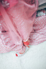 Closeup detail of bride putting on high heeled sandal wedding shoes. Selective focus.