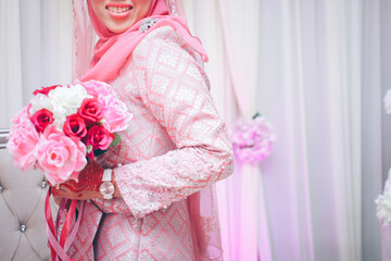 Close up of bride's hand with henna painted wearing wedding ring holding a rose bouquet in...
