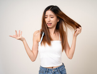 Young asian woman having problems with her hair Thin damaged dry hair falls out easily and is not healthy have to cut off. Standing on isolated white background