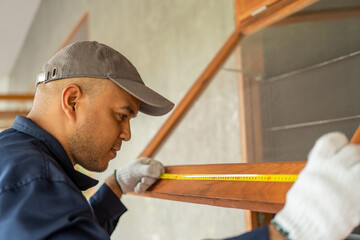 Technician worker in uniform using measuring tape tool to measuring wood window in the home...