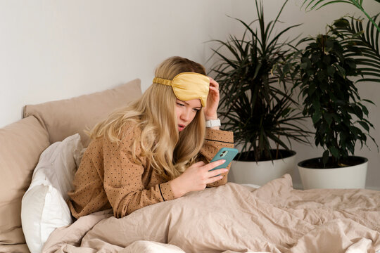 Woman in bed checking phone, concerned look.
