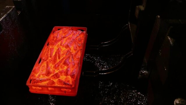 hardening process of metal parts, controlled cooling with oil and water quenching. hot red heated forged iron steel components pieces dipping in water oil bath with scada system