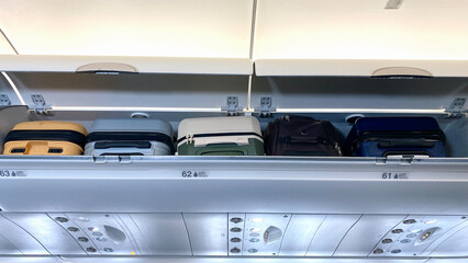 Luggage shelf with luggages in an airplane. Aircraft interior. Travel concept.