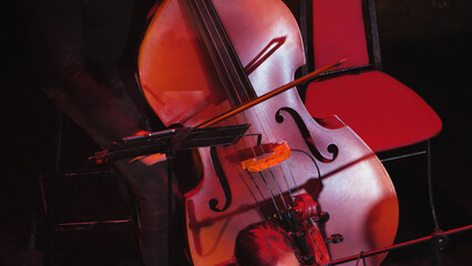 Close-up of a cello, a classical stringed instrument known for its deep, rich sound. The bow used...