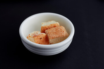 3 sliced small bread rectangle shape are placed in a white cup isolated on black background.