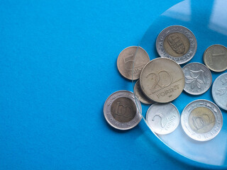 Hungarian forint coins under magnifying glass on a blue background, copy space. Local currencies