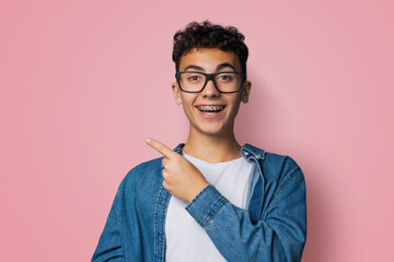 Excited happy black curly haired man in braces, open mouth, wear glasses denim shirt advertise show...