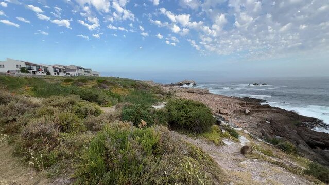 Sea view homes and apartments on the whale coast of Hermanus at sunset with a hyrax on the cliff path