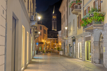 Lecco city, Italy. Downtown deserted city street scene at night. Town overlooking lake Como. Street Roma, square XX Settembre near the Viscontea tower and the bell tower of the Basilica of San Nicolò
