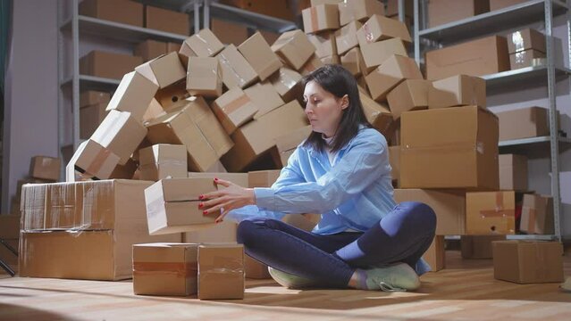 A young female worker scans boxes in a small warehouse