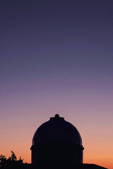 Obraz premium A large dome-shaped building is silhouetted against a purple sky