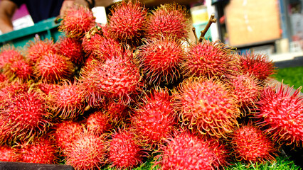 A bunch of red rambutans are piled on top of each other. Display at the street market during...