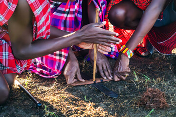 Making a fire by friction is most ancient way of making fire. It was used by ancient people, starting from the origins of history. Maasai mans making fire. - obrazy, fototapety, plakaty