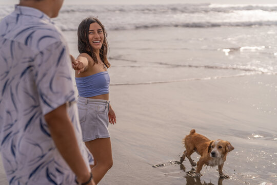 Couple in love and their dog playing on the seashore