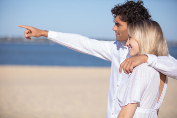 Fototapeta na wymiar loving couple on the beach pointing into the distance