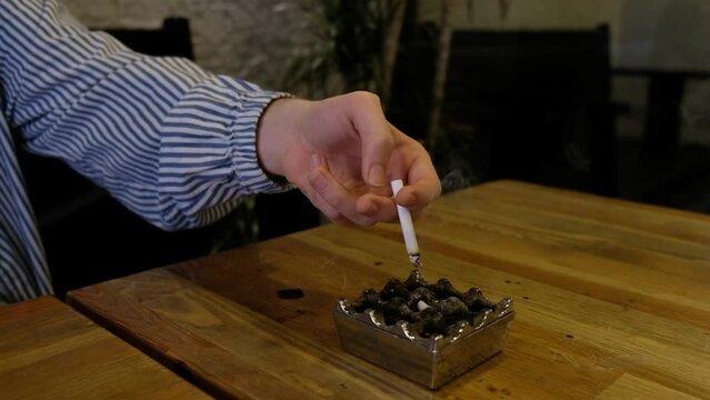 Throwing away cigarette ashes. Throwing cigarette ashes into the ashtray. Dropping the ash from the cigarette.
