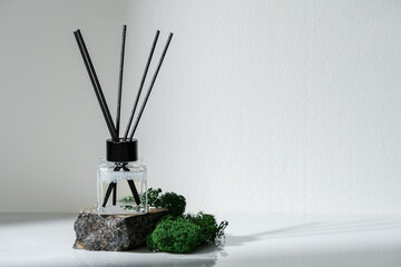 Elegant Aroma Diffuser With Black Reeds on a Granite Base Next to Moss Decor