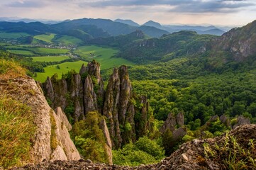Spring green mountain landscape with unique rock towers. View of a green valley with forests and...