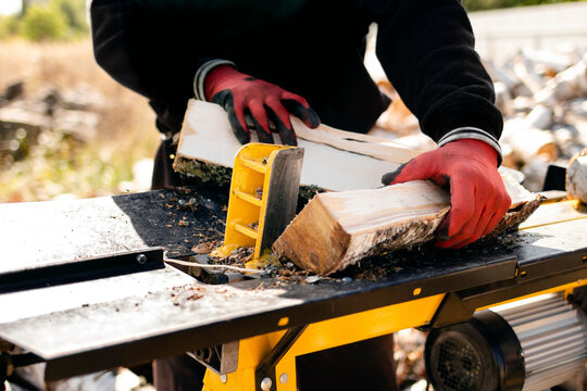 Close up of male hands chopping birch firewood on a hydraulic wood splitter. Sawmill. Birch firewood for fireplac