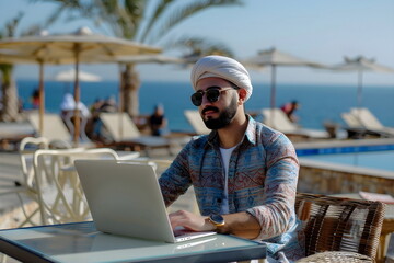 young arabian man working on a laptop in a beach bar