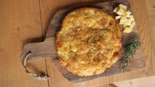 top down spinning shot of omlette made of cheese, potatos and eggs, decorated wooden plate