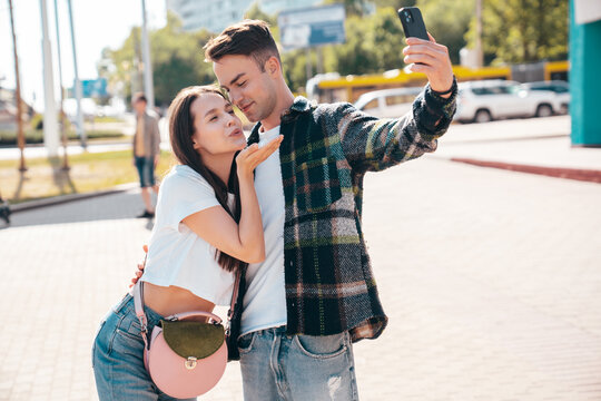 Smiling beautiful woman and her handsome boyfriend. Woman in casual summer clothes. Happy cheerful family. Female having fun. Sexy couple posing in the street at sunny day. Take selfie