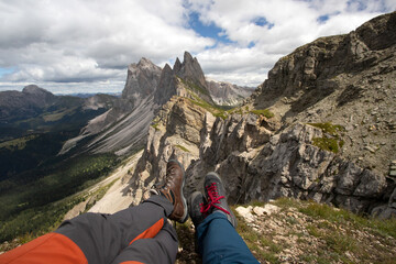 Trekking boots of a hiker couple while sitting on top of a mountain in Seceda, Dolomites, Italy - 775641765