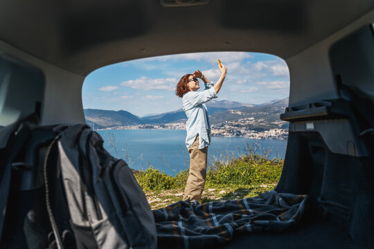 Young woman traveler looking for a mobile phone and internet signal while traveling by car at sea