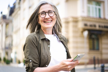 A woman wearing glasses is holding a cell phone in her hand.