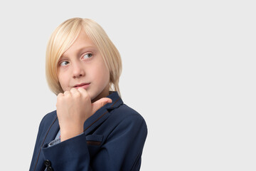 Thoughtful blond schoolboy with short haircut, keeps hand on chin, ponders something, isolated over...