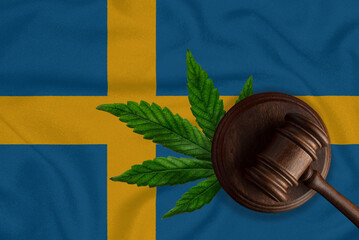 A gavel on the background of the flag of Sweden with a marijuana leaf. The concept of cannabis legalization in Sweden