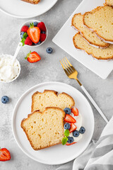Delicious vanilla pound cake served with fresh berries and whipped cream on a gray concrete background. Selective focus, copy space.