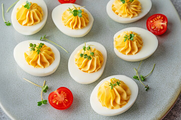 Deviled eggs with cheese, mustard and microgreens on top on a plate for Easter.