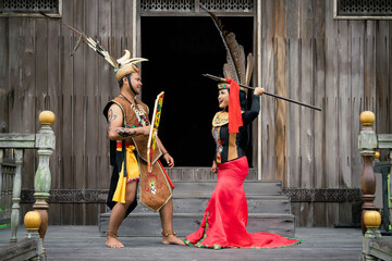 Portrait of man and woman wearing traditional Kalimantan Dayak clothing with the background of a...