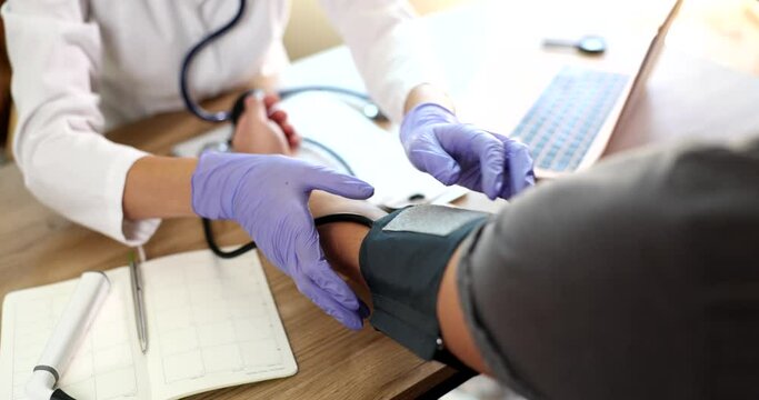 Doctor cardiologist therapist puts tonometer on fart of man in clinic. Normal blood pressure in humans age