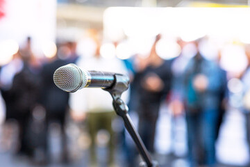 Microphone in focus against blurred audience. Public relations - PR concept.