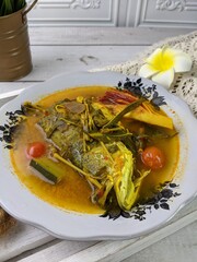 A plate of fish cooked in spicy sour sauce with herbs and vegetables. A popular Malaysian dish...