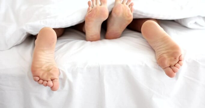 Legs of couple of woman and man in bed. Intimate love life and sex