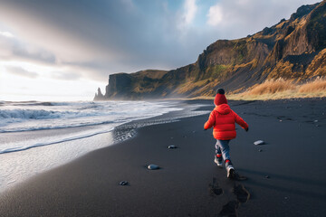 Happy child running on black sand volcanic beach in Iceland. - obrazy, fototapety, plakaty