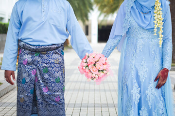Malay wedding theme, holding hands newlyweds. Beautiful young adult couple.