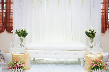 Minimalist Malay wedding stage decorations with flowers and leaf.