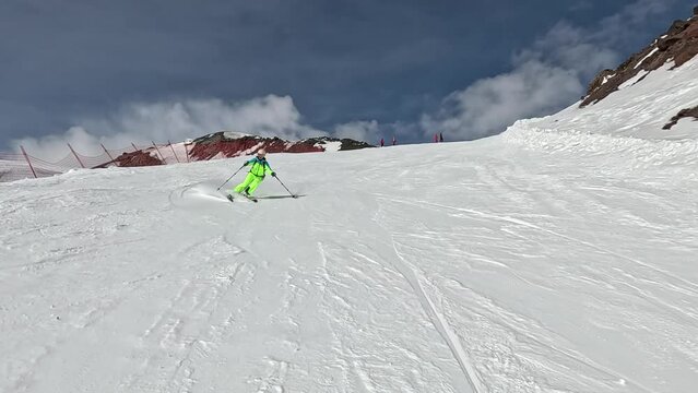 Skier turns sides with good ski technique on ski slope in mountain resort. Skiing in winter with best mountain scenery is absolute freedom and positive emotions of extreme sports. Front view in motion