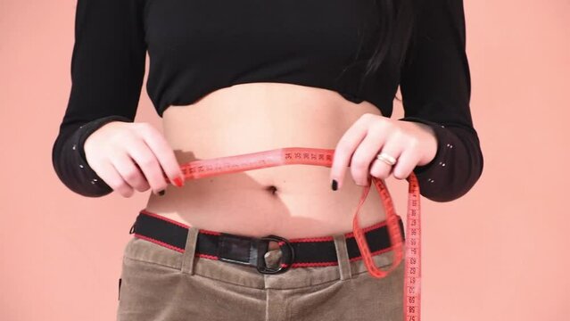 Slim girl measures  waist circumference with measuring tape, diet and healthy lifestyle. Horizontal 4k footage