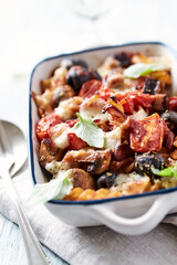 Baked pasta with cherry tomatoes, olives and mozzarella cheese. Bright wooden background. Close up.	