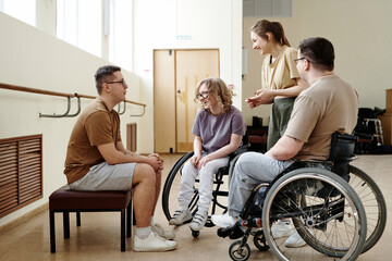 Goup of wheelchair dancers and their trainers spending break time together chatting and laughing