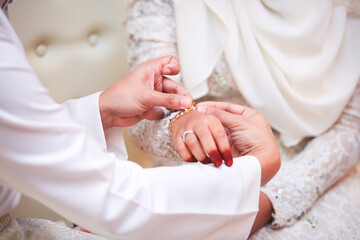 Obraz na płótnie Canvas The groom fastens the bracelet on the bride's wrist. Close up and selective focus.
