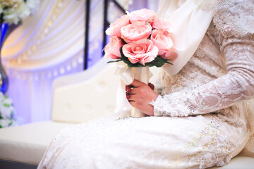 Malay girl in a wedding dress holds in her hands a bouquet of flowers. Malay wedding concept.